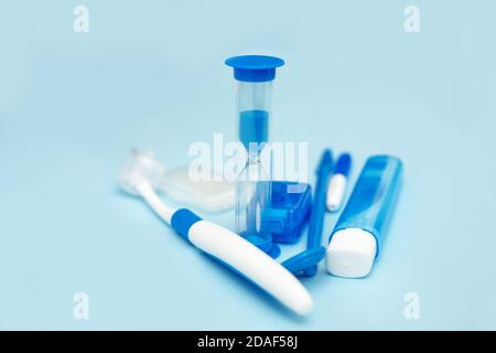 Mundhygiene beim Tragen von Zahnspangen, Zahnspangen, Home Care Kit, zahnärztliche Instrumente, Zahnseide, Zahnbürsten, Sanduhr. Zahnkonzept auf einem blauen Stockfoto