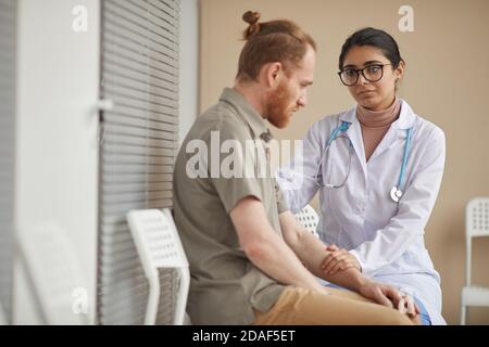 Männlicher Patient verärgert durch Nachrichten des Arztes, während sie an sitzen Der Korridor des Krankenhauses Stockfoto