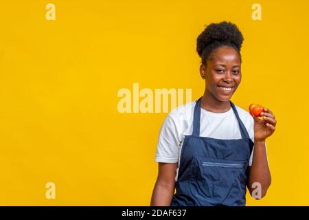 Porträt einer weiblichen afrikanischen Köchin lächeln und halten ein Tomate Stockfoto