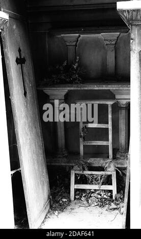 Dramatisches offenes Grab mit einer ernsten alten Frau und der Tür aufgerissen in einem verlassenen Friedhof in schwarz und Weißeffekt Stockfoto