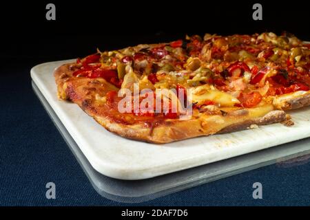 Die Pizza mit Wurst und Käse auf schwarzem Hintergrund. Backen auf dem Tisch. Produkte der Fütterung Stockfoto