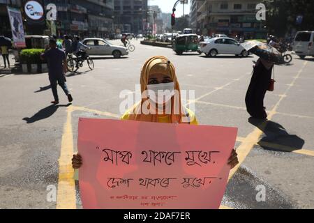 Ein Freiwilliger, der eine Gesichtsmaske trägt, zeigt während der Maskenaufklärungskampagne im Gulshan in Dhaka ein Plakat.Taskin Ahmed, Spieler des Bangladesh National Cricket Teams, eröffnet die Eröffnungszeremonie von "wo ist deine Maske?" Kampagne der JAAGO Foundation in Gulshan. Diese Kampagne zielte darauf ab, Menschen zu ermutigen, Gesichtsmasken während der Coronavirus-Pandemie zu tragen, um ihre Sicherheit und andere zu gewährleisten. Stockfoto