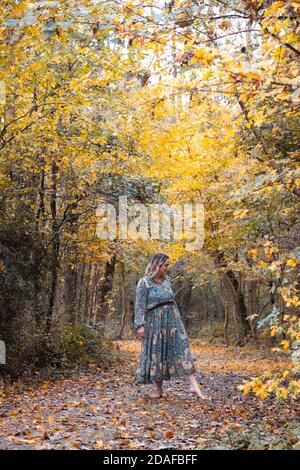Dame mit langem Kleid zu Fuß durch den Wald, Herbst gelbe Blätter Stockfoto