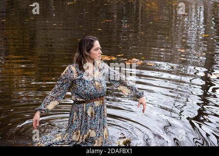 Dame in einem Kleid, im Wasser an einem Herbsttag Stockfoto