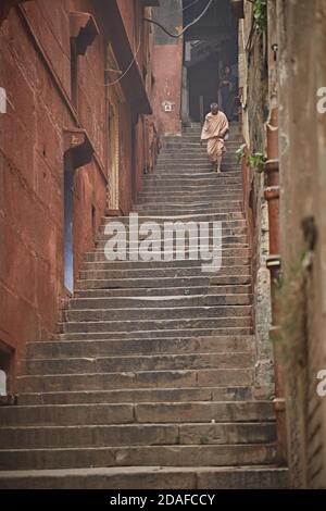 Varanasi, Indien, Dezember 2015. Ein Mann steigt lange Treppen in einem Ghat am Ganges River hinab. Stockfoto