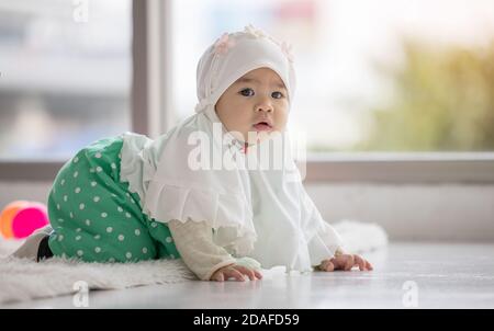 Liebenswert kleine muslimische Baby Mädchen auf dem Boden liegend Blick auf Kamera. Stockfoto