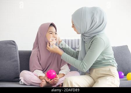 Portrait von glücklich schöne Familie arabisch muslimische Mutter und wenig muslimische Mädchen Kind mit Hijab Kleid lächelnd und Spaß haben Umarmen und küssen zusammen Stockfoto