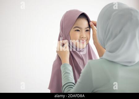 Portrait von glücklich schöne Familie arabisch muslimische Mutter und wenig muslimische Mädchen Kind mit Hijab Kleid lächelnd und Spaß haben Umarmen und küssen zusammen Stockfoto