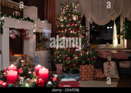 Es ist Heiligabend. Die Kerzen auf dem Adventskranz brennen, der Baum ist geschmückt. Weihnachtsgeschenke sind unter dem Baum. Stockfoto