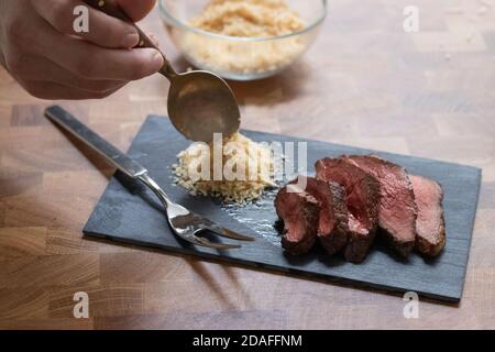 Picanha Fleisch, brasilianisches Kuhsteak, serviert mit Farofa an einem Holztisch Stockfoto