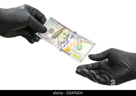 Konzept der Korruption. Zwei Hände in schwarzen Gummihandschuhen. Einer gibt den anderen 100-Dollar-Schein. Isoliert auf weißem Hintergrund Stockfoto