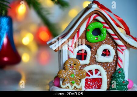 Weihnachten Lebkuchen Haus Dekoration auf dem Hintergrund der entkochten goldenen Lichter. Handdekoriert. Stockfoto