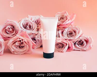 Mockup hellrosa Squeeze Flasche Plastikschlauch mit schwarzer Kappe und rosa Rosen auf pastellrosa Hintergrund. Flasche für Branding und Etikett. Natürlich organisch Stockfoto