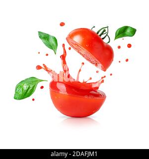 Spritzt Tomatensaft mit fliegenden Basilikumblättern isoliert auf weißem Hintergrund. Designelement für Produktetikett. Stockfoto