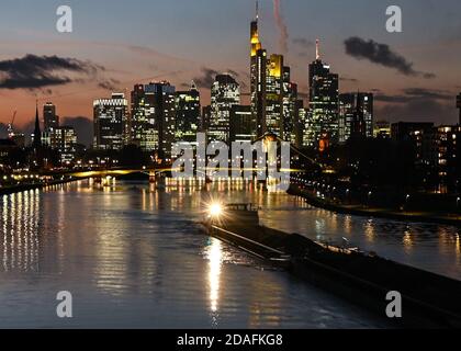 12. November 2020, Hessen, Frankfurt/Main: Ein Frachtschiff fährt auf dem Main, während die Sonne hinter den beleuchteten Wolkenkratzern der Bankenstadt untergeht. Foto: Arne Dedert/dpa Stockfoto