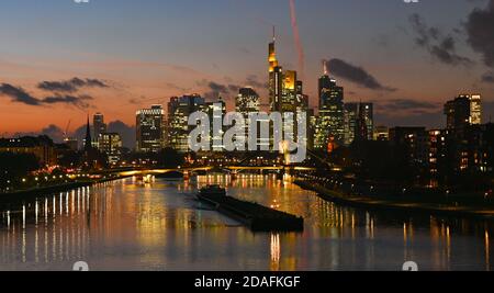 12. November 2020, Hessen, Frankfurt/Main: Ein Frachtschiff fährt auf dem Main, während die Sonne hinter den beleuchteten Wolkenkratzern der Bankenstadt untergeht. Foto: Arne Dedert/dpa Stockfoto