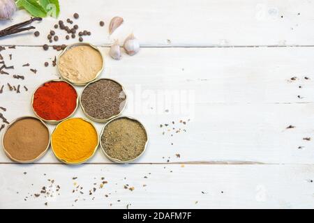 Gewürze verschiedener Art und Farben. Auf dem weißen alten Holztisch. Zutaten, die unserer Küche den richtigen Geschmack verleihen. Stockfoto