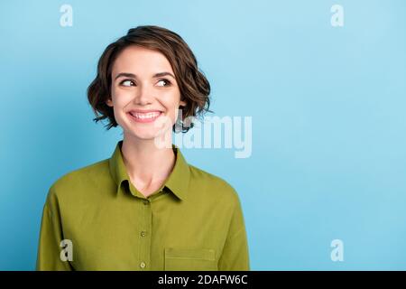 Foto-Portrait von lustigen positiven weiblichen Schüler mit welligen Haaren Und kurze Frisur trägt grüne Hemd lächelnd lachend Blick auf Seite isoliert auf blau Stockfoto