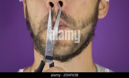 Schöner junger Kerl trimmt seinen Bart mit einer Schere. Stockfoto