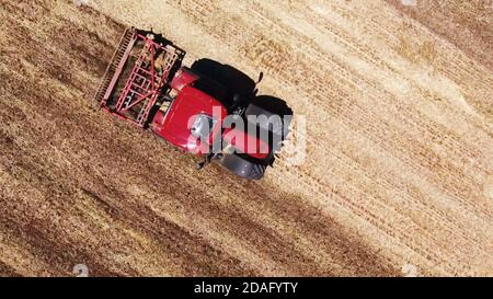 Oben Luftaufnahme der Landwirtschaft roten Traktor pflügen das Feld, Land Pflug Stockfoto