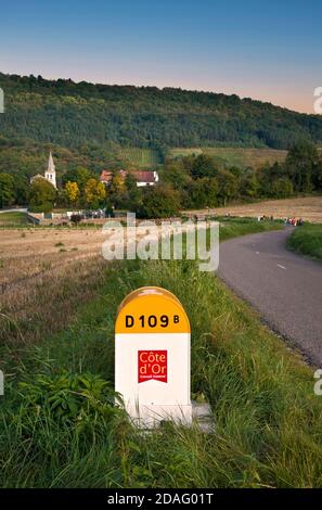 Hautes Cotes de Nuits Landstraße Schild D109 Markierpfosten, Stein Straßenrand Marker & Curtil-Vergy Dorf hinter mit Wanderern, Cote d'Or, Bourgogne Frankreich Stockfoto