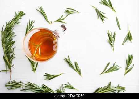 Kräutertee mit Rosmarin in einer Glasschale auf weißem Holzhintergrund mit Platz für Text. Rosmarintee. Artikel, Poster. Stockfoto