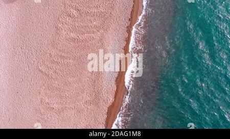 Top Luftaufnahme von einem schönen Sandstrand und transparentem türkisfarbenem Meerwasser. Stockfoto
