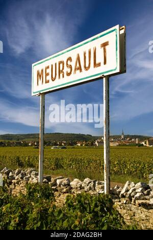 Meursault rustikales Weindorf Grenzschild mit burgunderroten Weinbergen, Dorf und Kirche dahinter, Cote d'Or. Frankreich Stockfoto