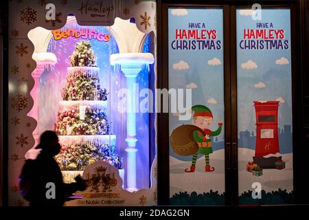 Ein Mitglied des Publikums geht an den weihnachtlichen Schaufenstern vor dem geschlossenen Hamleys Spielzeugladen, Regent Street London vorbei. Stockfoto