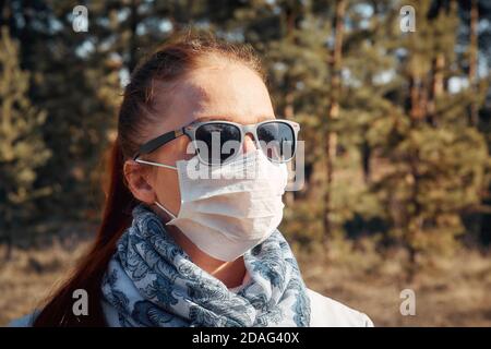 Schutz vor Krankheiten und Coronavirus, trägt die Frau eine medizinische Maske und Sonnenbrille. Frühjahrsmode 2020 Stockfoto