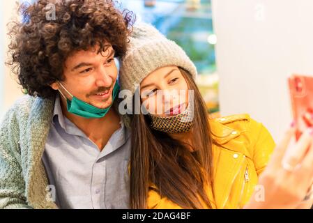 Junge Leute, die Selfie innen tragen Gesicht schützende masks.Coronavirus Prävention, Reisen sicher, Technologie-Trends und Herbst Urlaub Konzept. Stockfoto