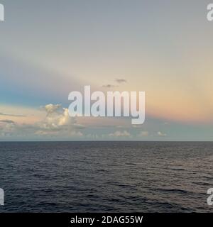 Ein wunderschöner rosa, blau und orange Sonnenuntergang über dem karibischen Meer an einem verschwommenen Abend. Stockfoto