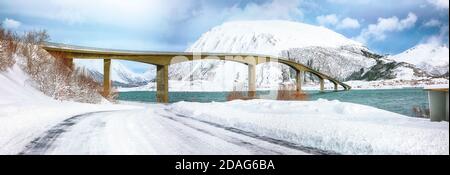 Dramatische Winterszene der Gimsoyststraumen Brücke mit viel Schnee und schneebedeckten Berggipfeln. Lage: Gemeinde Vagan, Landkreis Nordland, Lofotens Stockfoto