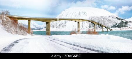 Dramatische Winterszene der Gimsoyststraumen Brücke mit viel Schnee und schneebedeckten Berggipfeln. Lage: Gemeinde Vagan, Landkreis Nordland, Lofotens Stockfoto