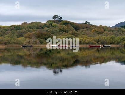 Ruhige Landschaft mit Fischerbooten und Reflexionen auf einem ruhigen See am Lough Leane im Killarney Nationalpark, Grafschaft Kerry, Irland Europa Stockfoto