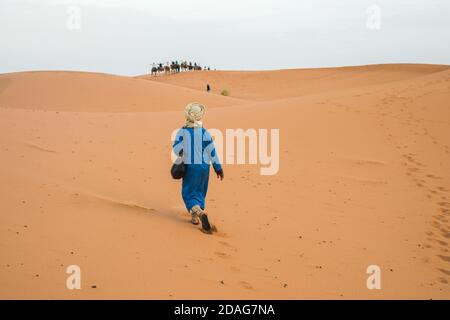 Merzouga, Marokko - APRIL 29 2019: Marokkaner auf dem Weg zu den Kamelen in der Sahara Stockfoto