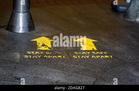 Stay Safe Stay Apart schablonierte gelbe Straßenschilder für soziale Distanzierung in Birmingham, Großbritannien Stockfoto