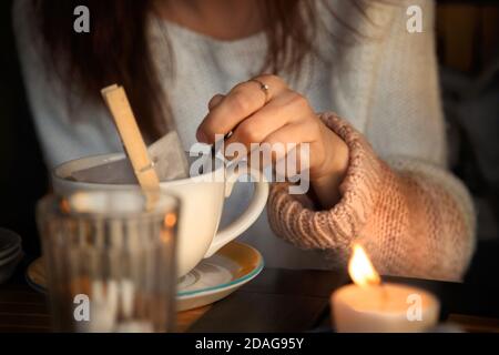 Frau rührt Zucker in einer Tasse Tee. Herbststimmung. Gemütliche Herbstkomposition. Hygge-Konzept. Weichfokus Stockfoto