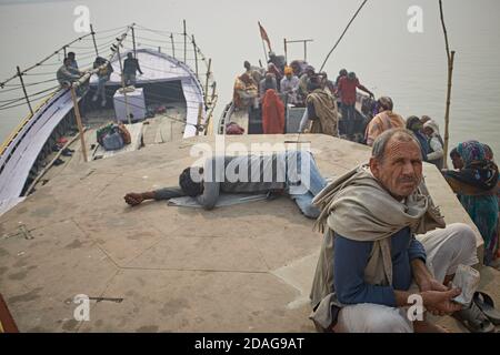 Varanasi, Indien, Januar 2016. Pilger in einem Ghat am Ganges Fluss neben großen Booten. Stockfoto