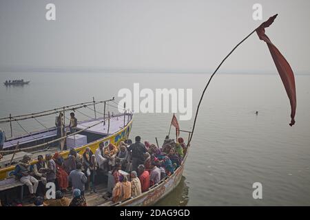 Varanasi, Indien, Januar 2016. Pilger in einem Ghat am Ganges Fluss neben großen Booten. Stockfoto