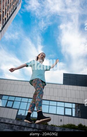 Blick von unten auf stilvolle Teenager in der Nähe Wolkenkratzer zu Fuß im Freien Stockfoto