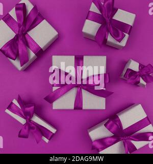 Geschenkschachteln in Bastelpapier mit violetten Bändern und Schleifen verpackt. Festliche einfarbige flache Lay. Stockfoto