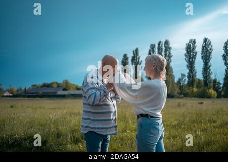 Älterer Mann hält und küsst Frau Hand auf Datum in parken Stockfoto