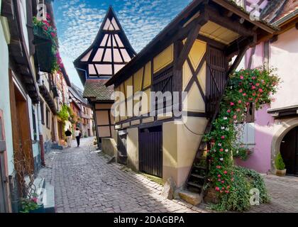 EGUISHEIM Rue du Rempart Eguisheim mittelalterliches Weindorf mit Touristen Paar zu Fuß die historische gepflasterte Straße Eguisheim Elsass Frankreich Stockfoto