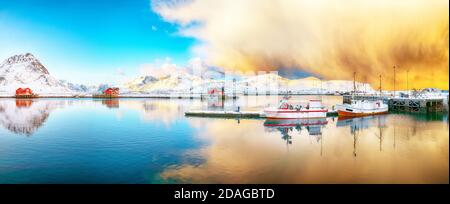 Erstaunlicher Wintersonnenaufgang über Ramberg Dorf und Hafen. Festgemacht Fischerschiffe im Hafen. Lage: Ramberg, Flakstadoya Insel, Lofoten; Norwegen, Europa Stockfoto