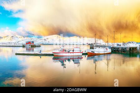 Erstaunlicher Wintersonnenaufgang über Ramberg Dorf und Hafen. Festgemacht Fischerschiffe im Hafen. Lage: Ramberg, Flakstadoya Insel, Lofoten; Norwegen, Europa Stockfoto