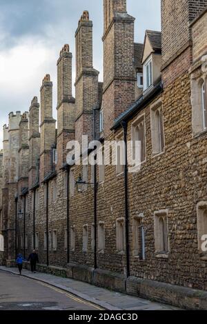 Eine Reihe von historischen Steinhäusern mit Terrassen in der Universitätsstadt cambridge mit zwei Personen, die auf dem Bürgersteig spazieren. Stockfoto