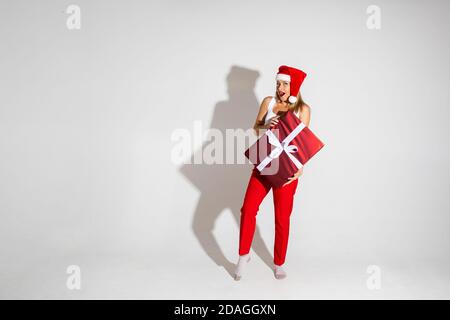Schöne Frau mit rot und weiß weihnachtshut hält ein Große Box mit Geschenk Stockfoto