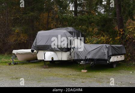 Ein Freizeitanhänger, Boot und Zeltanhänger sind abgedeckt und in Planen gewickelt, um vor Winterwetter zu schützen Stockfoto