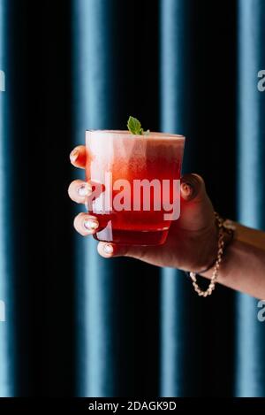 Roter Erdbeer alkoholischer Cocktail in der Hand einer Frau Stockfoto